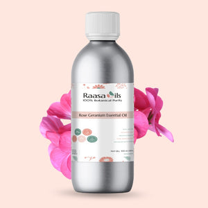 Bottle of Raasa Oils Rose Geranium Essential Oil with pink flowers on a light pink background