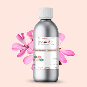 Bottle of Raasa Oils Rose Geranium Fragrance Oil with pink flowers on a light pink background