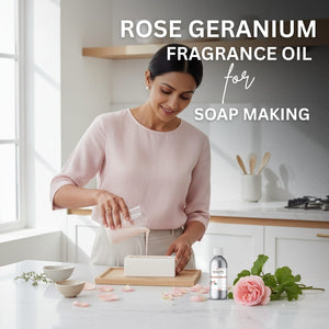 Woman in a kitchen preparing soap with rose geranium fragrance oil, surrounded by flowers and a bottle of the product.