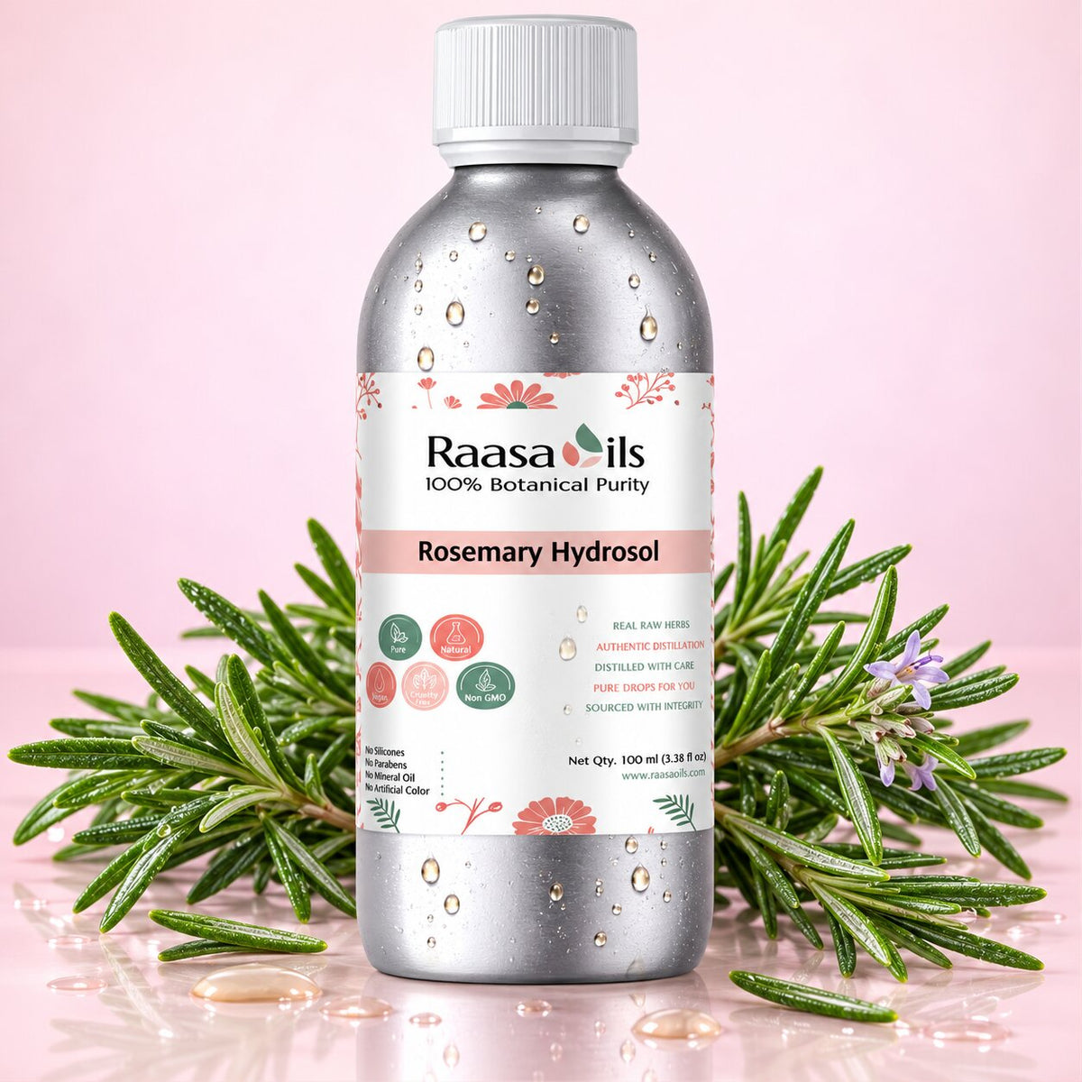 A bottle of Raasa Oils Rosemary Hydrosol centered on a pink background, flanked by green rosemary sprigs with small purple flowers. The bottle is metallic silver with a white cap and a white label featuring pink floral graphics and product text.