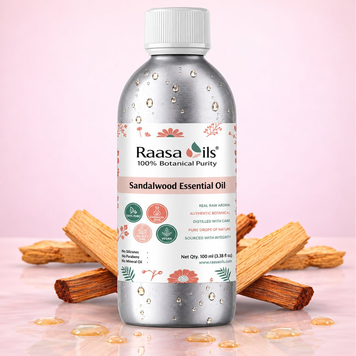 A bottle of Raasa Oils Sandalwood Essential Oil centered on a soft pink background, surrounded by scattered sandalwood pieces and a few drops of oil on a reflective surface.