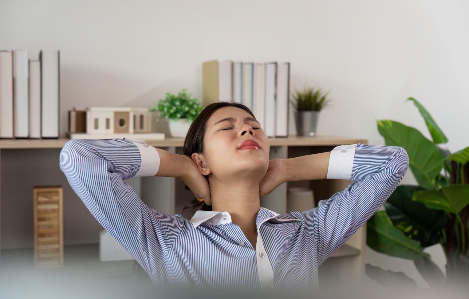 Woman relaxing with hands behind head in a home office setting
