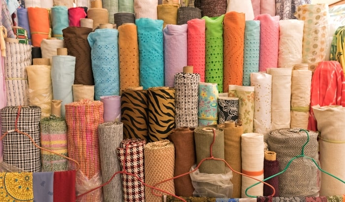 Collection of various colorful fabric rolls stacked together