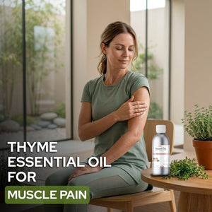 Woman applying thyme essential oil to her arm with a bottle of thyme essential oil on a table.
