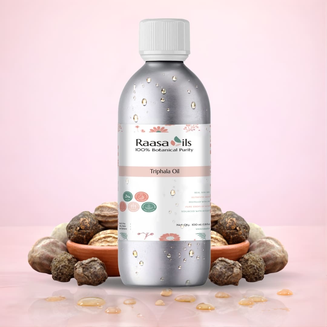Bottle of Raasa Oils Triphala Oil with Triphala fruits on a pink background