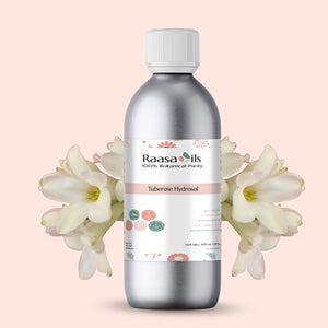 Bottle of Raasa Oils Tuberose Hydroal on a light pink background with white flowers.