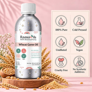 A bottle of Raasa oils Wheat Germ Oil stands on a wooden tray surrounded by wheat stalks and seeds, with a pink background and a product information panel showing icons for 100% Pure, Cold Pressed, Undiluted, Vegan, Cruelty Free, and No Synthetic Additives.